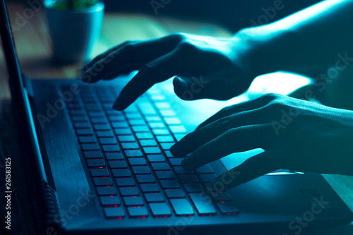 A computer programmer or hacker prints a code on a laptop keyboard to break into a secret organization system.
