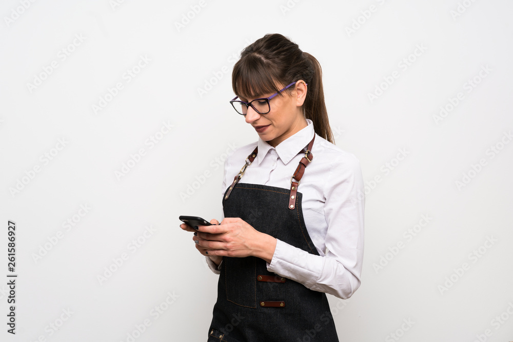 Young woman with apron sending a message with the mobile Young woman with apron sending a message with the mobile