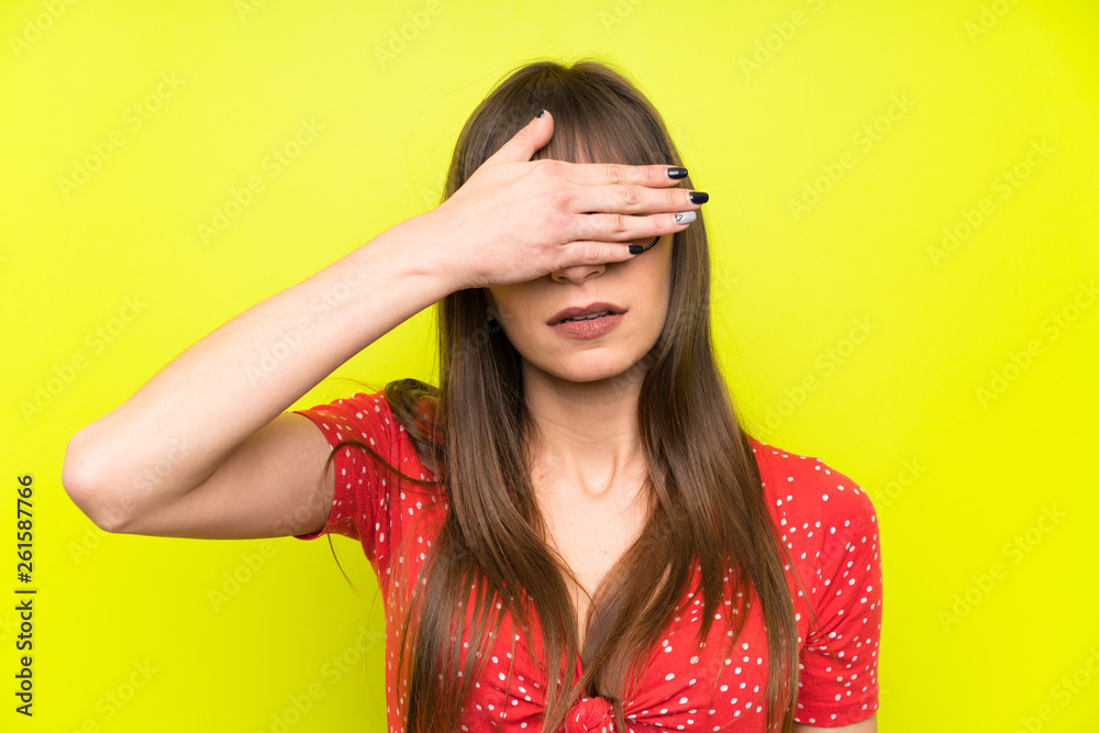 Young woman over green wall covering eyes by hands Young woman over green wall covering eyes by hands