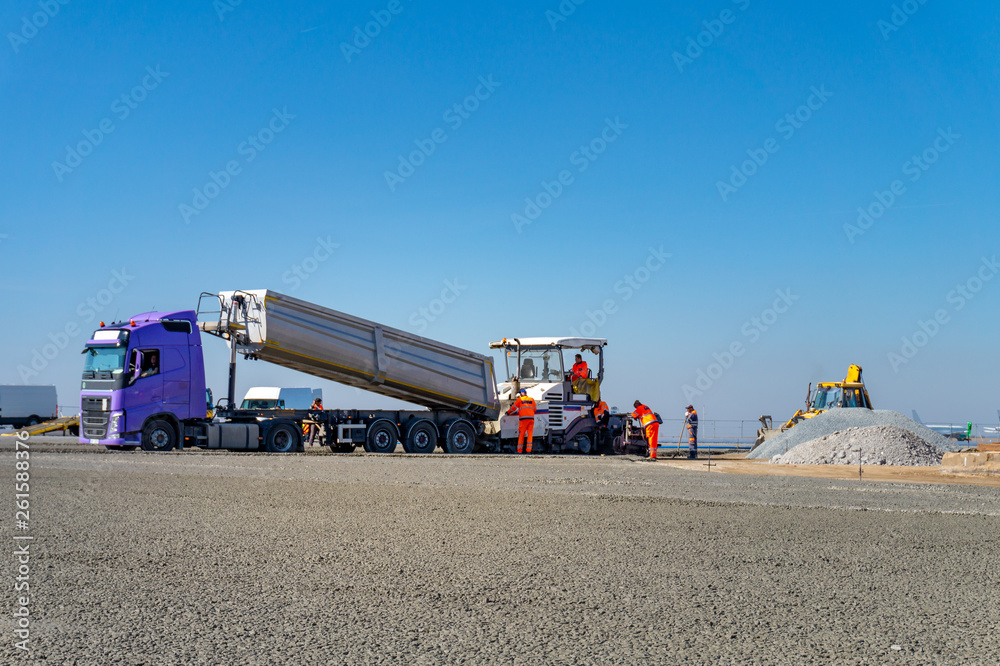 Construction site of road, building or airport with construction machinery (truck, bulldozer, excavator) and construction workers or engineers Construction site of road, building or airport with construction machinery (truck, bulldozer, excavator) and construction workers or engineers