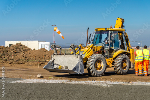 Construction site of road, building or airport with construction machinery (truck, bulldozer, excavator) and construction workers or engineers