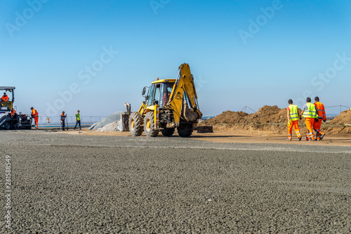 Construction site of road, building or airport with construction machinery (truck, bulldozer, excavator) and construction workers or engineers