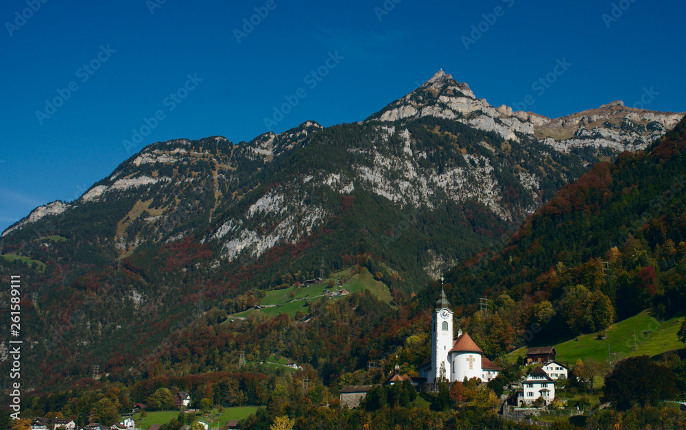 Church below forest covered mountain side