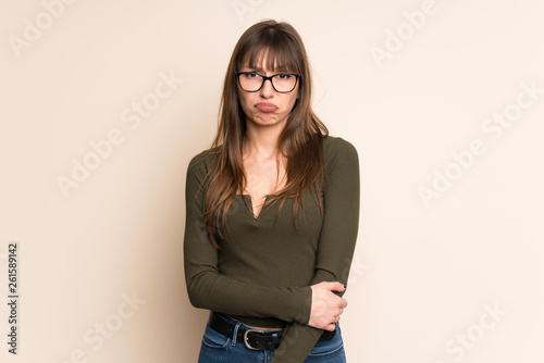 Young woman on ocher background with sad and depressed expression