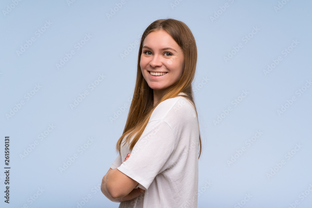 Young woman over blue wall with arms crossed Young woman over blue wall with arms crossed