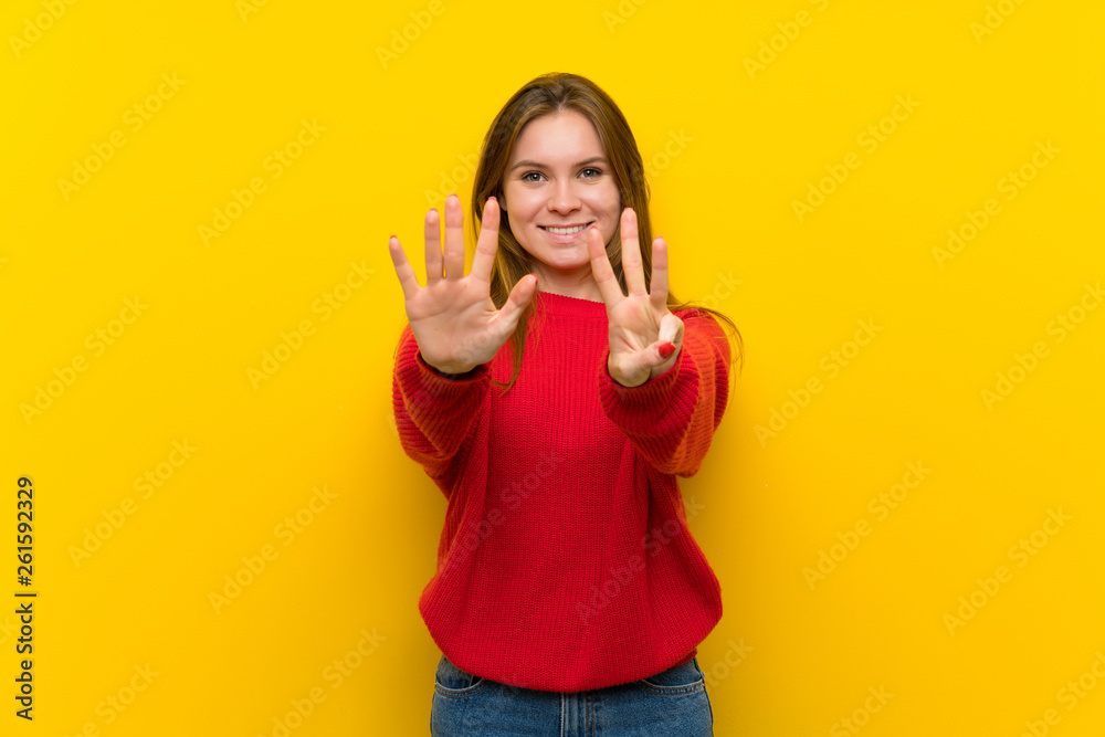 Young woman over yellow wall counting eight with fingers Young woman over yellow wall counting eight with fingers