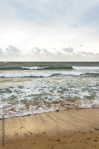 Blue and green waves with white foam on sandy beach. Black Sea, Evpatoria, Crimea, Russia. Travel, wacation concept. Text copy space.