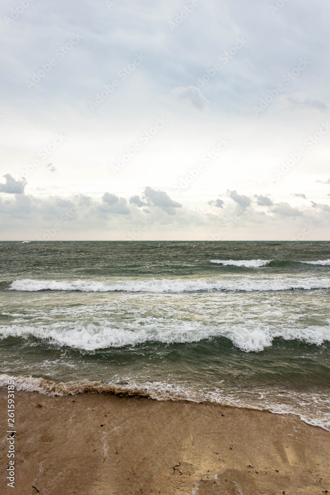 Blue and green waves with white foam on sandy beach. Black Sea, Evpatoria, Crimea, Russia. Travel, wacation concept. Text copy space.