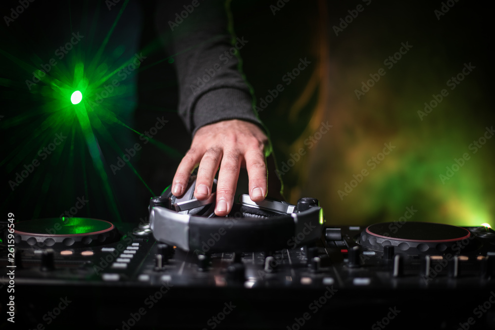 DJ Spinning, Mixing, and Scratching in a Night Club, Hands of dj tweak various track controls on dj's deck, strobe lights and fog, or Dj mixes the track in the nightclub at party. DJ Spinning, Mixing, and Scratching in a Night Club, Hands of dj tweak various track controls on dj's deck, strobe lights and fog, or Dj mixes the track in the nightclub at party.
