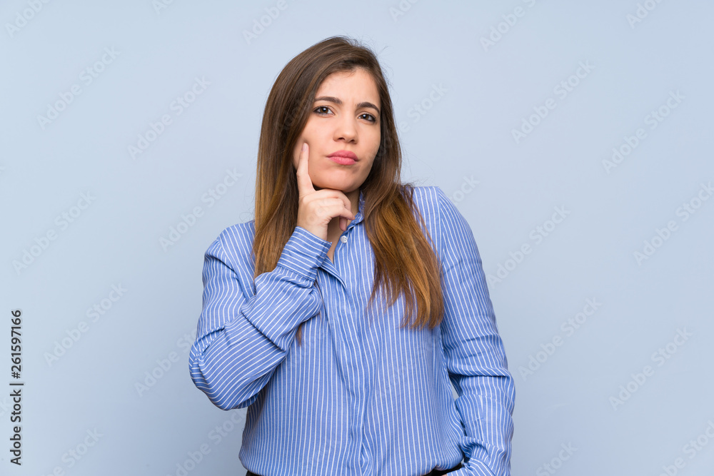 Young girl over isolated blue wall thinking an idea while looking up Young girl over isolated blue wall thinking an idea while looking up