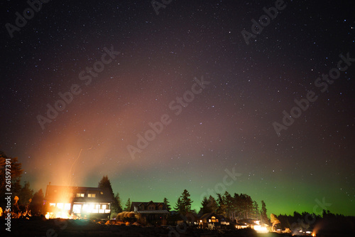 Cabins on the Coast of Canada with Northern Lights Above and Smoke from a Campfire