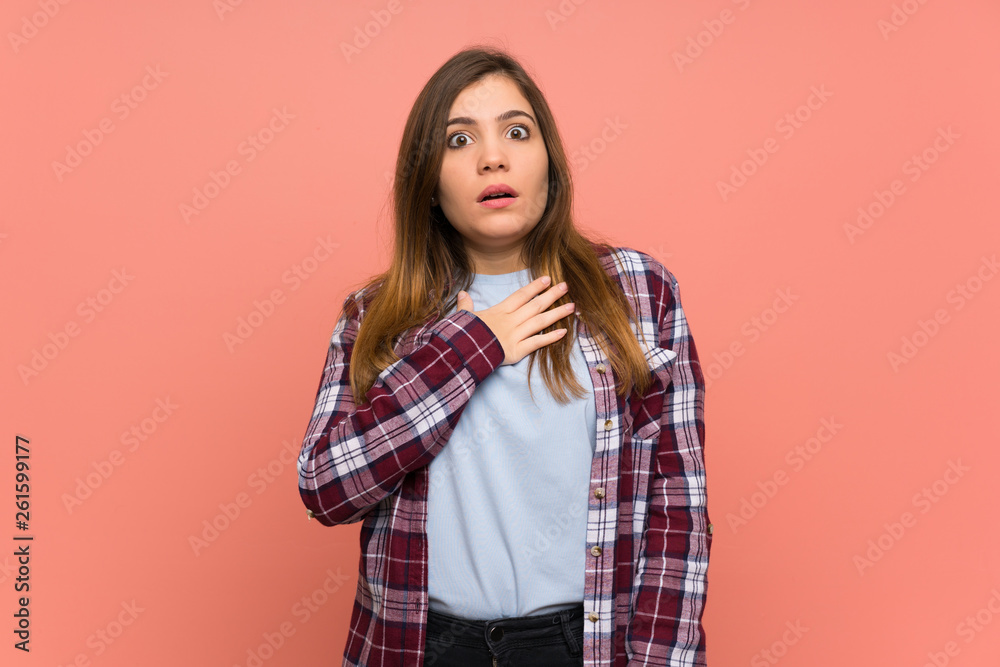 Young girl over pink wall surprised and shocked while looking right Young girl over pink wall surprised and shocked while looking right
