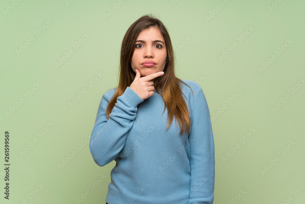 Young girl over green wall thinking Young girl over green wall thinking