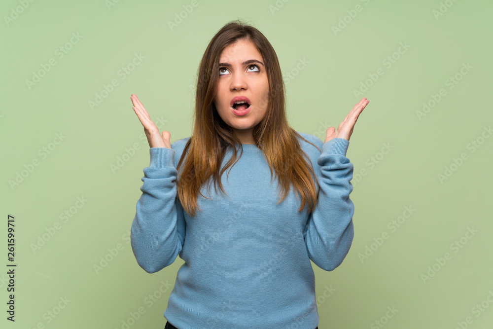Young girl over green wall frustrated by a bad situation