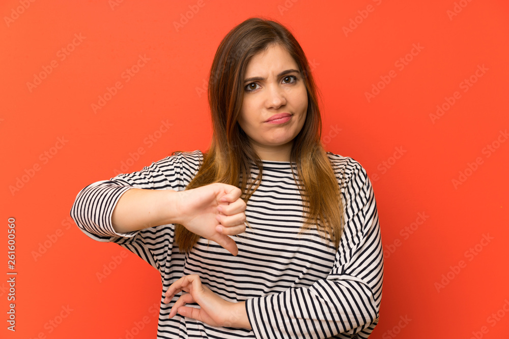 Young girl with striped shirt showing thumb down sign Young girl with striped shirt showing thumb down sign