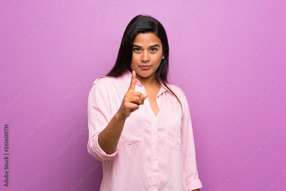 Young Colombian girl over purple wall frustrated and pointing to the front Young Colombian girl over purple wall frustrated and pointing to the front