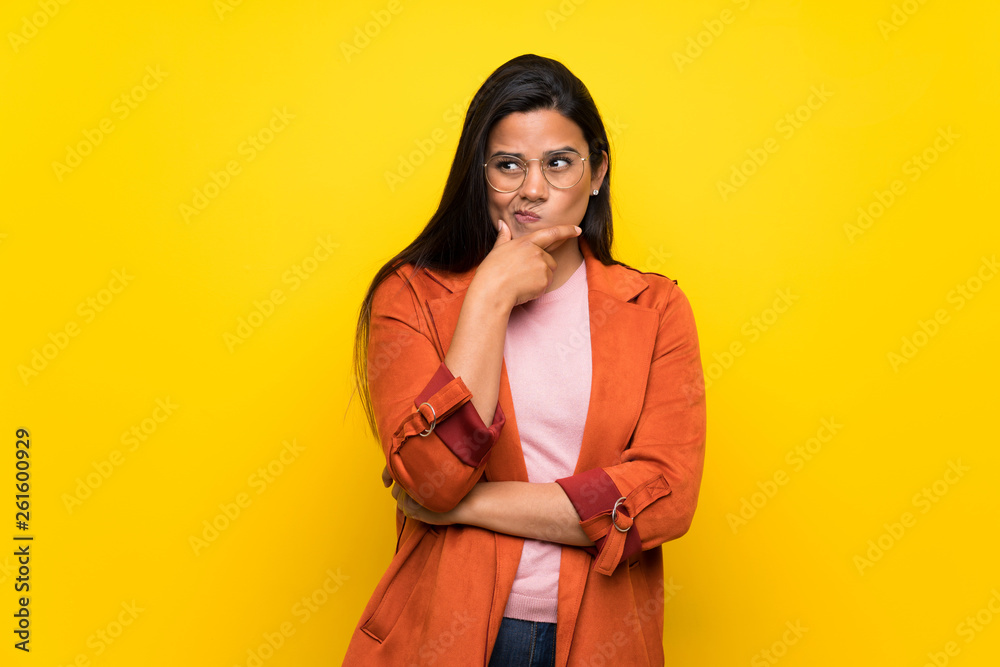 Young Colombian girl over yellow wall looking to the front Young Colombian girl over yellow wall looking to the front