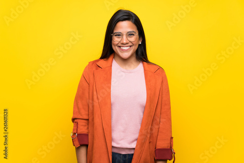 Young Colombian girl over yellow wall with glasses and happy © luismolinero