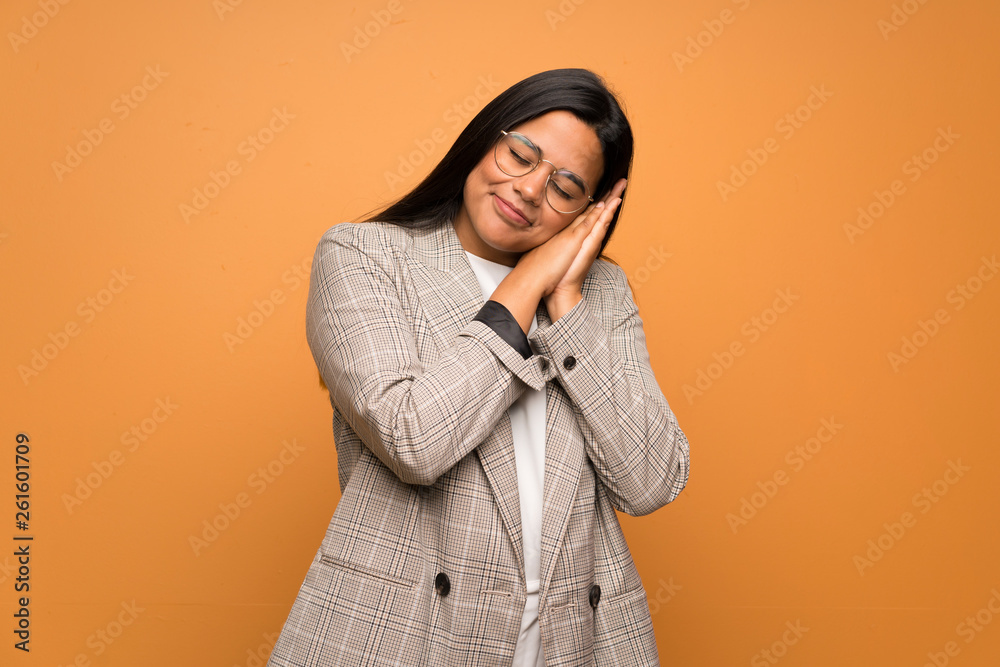 Young Colombian girl over brown wall making sleep gesture in dorable expression