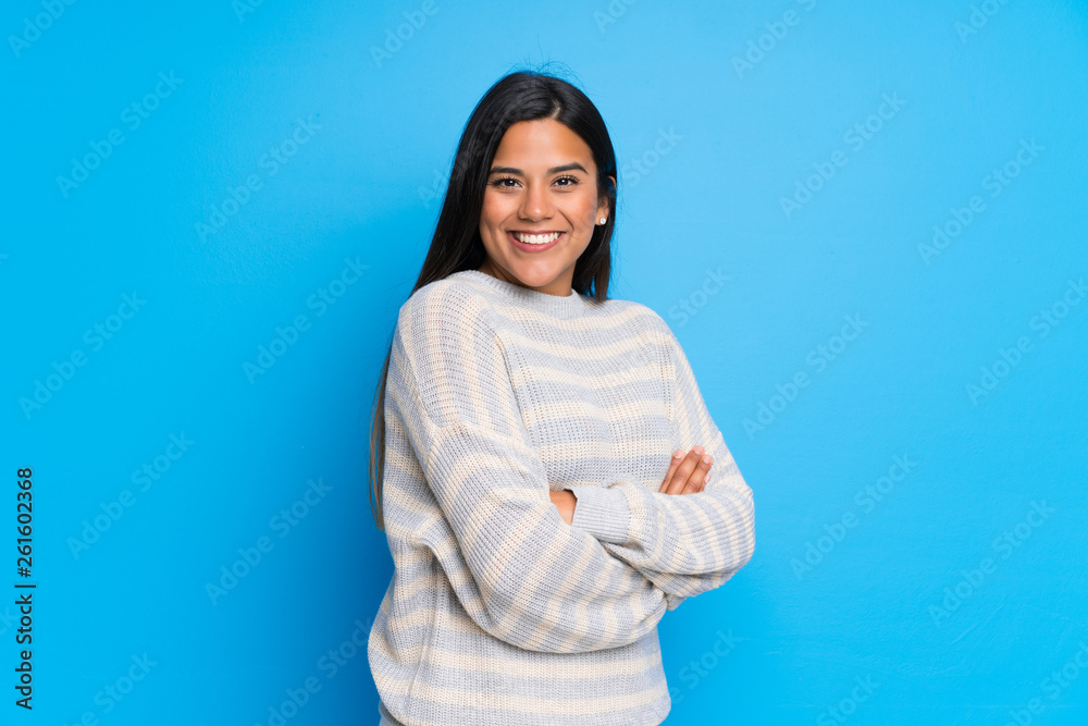 Young Colombian girl with sweater keeping the arms crossed in lateral position while smiling Young Colombian girl with sweater keeping the arms crossed in lateral position while smiling