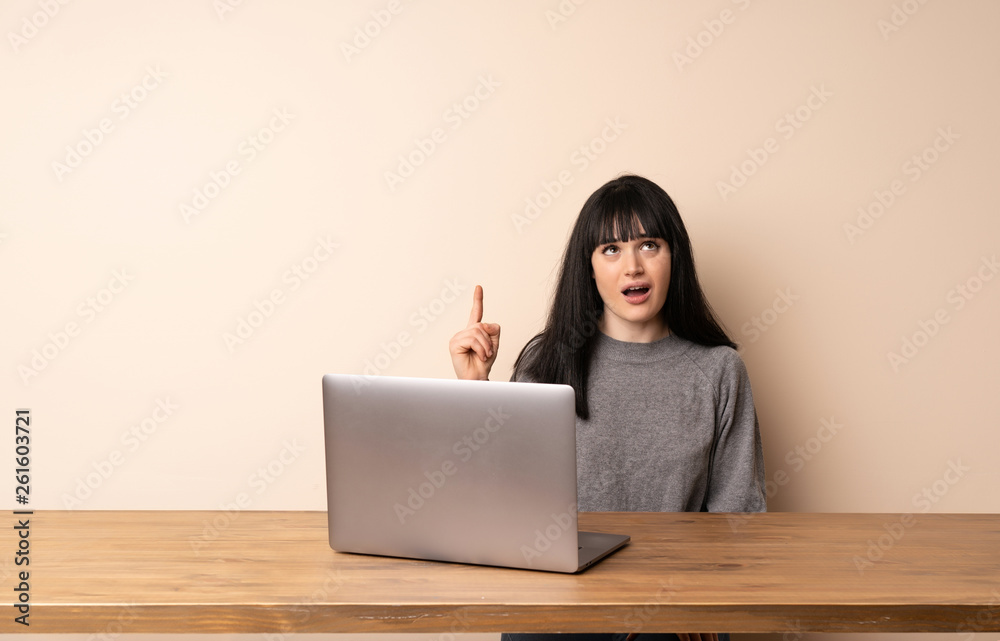 Young woman working with her laptop pointing up and surprised Young woman working with her laptop pointing up and surprised
