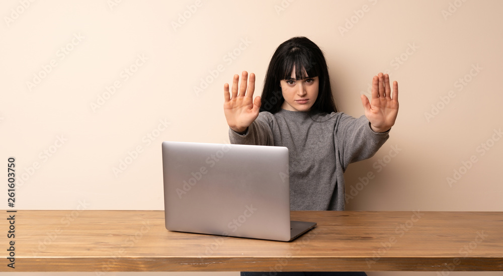 Young woman working with her laptop making stop gesture and disappointed Young woman working with her laptop making stop gesture and disappointed