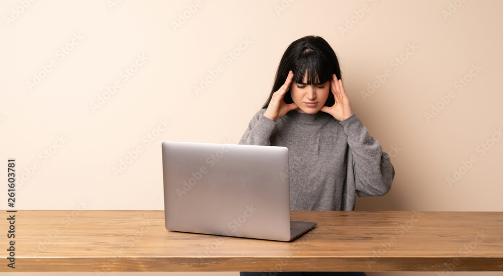 Young woman working with her laptop with headache Young woman working with her laptop with headache