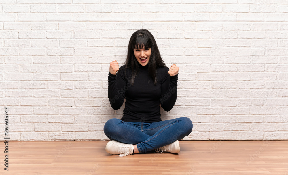 Woman sitting on the floor celebrating a victory in winner position