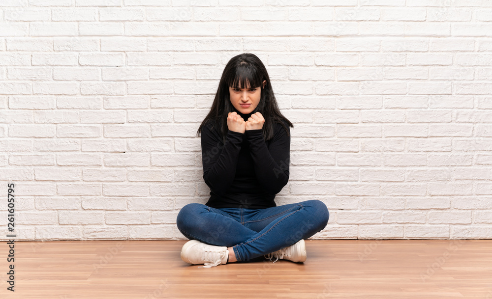 Woman sitting on the floor frustrated by a bad situation Woman sitting on the floor frustrated by a bad situation