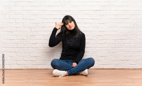 Woman sitting on the floor with problems making suicide gesture