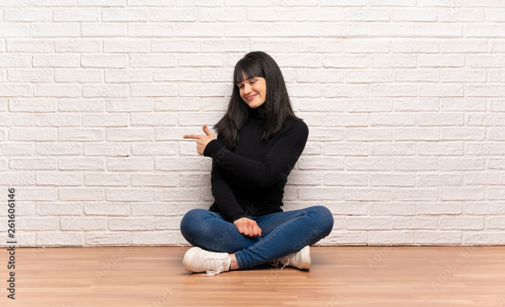 Woman sitting on the floor pointing back Woman sitting on the floor pointing back