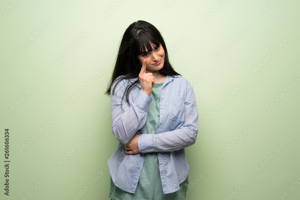 Young woman over green wall looking to the front