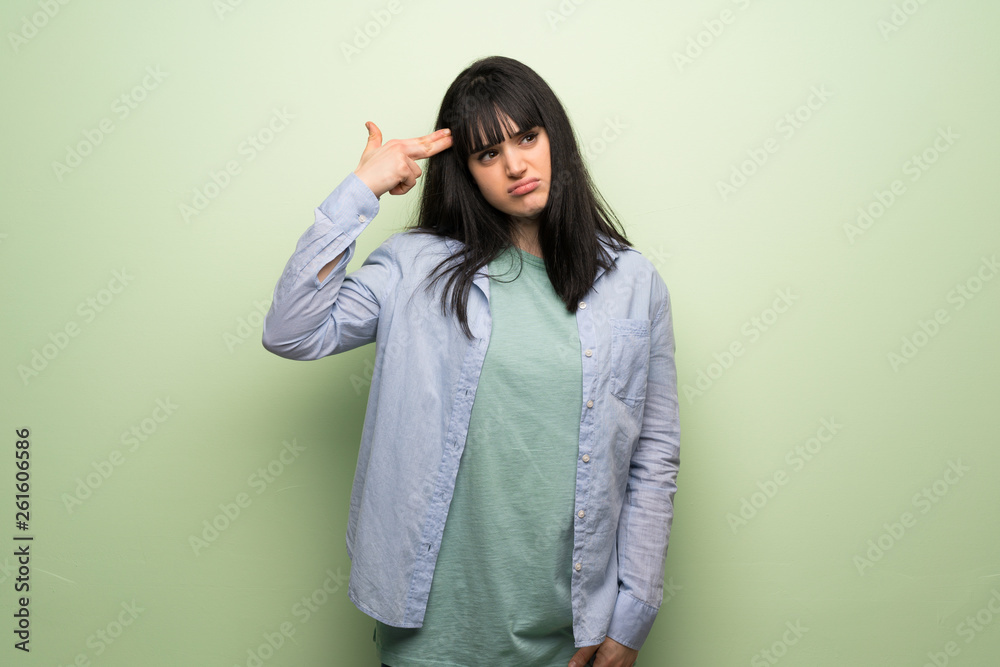 Young woman over green wall with problems making suicide gesture Young woman over green wall with problems making suicide gesture