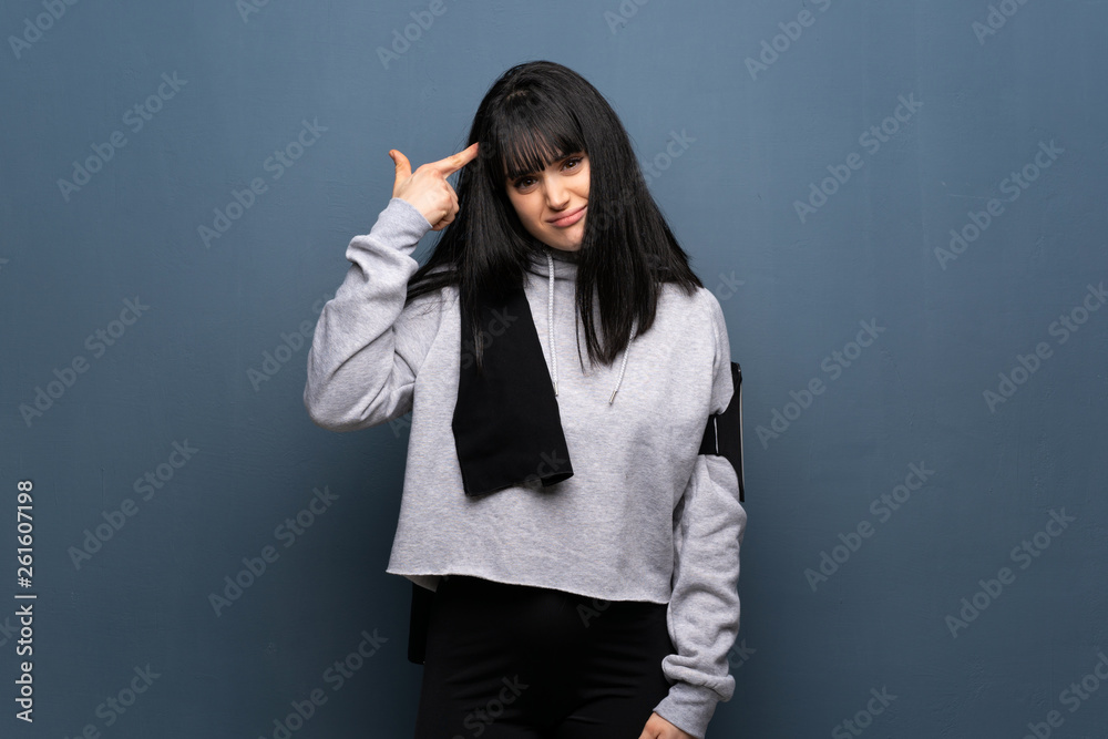 Young sport woman making the gesture of madness putting finger on the head