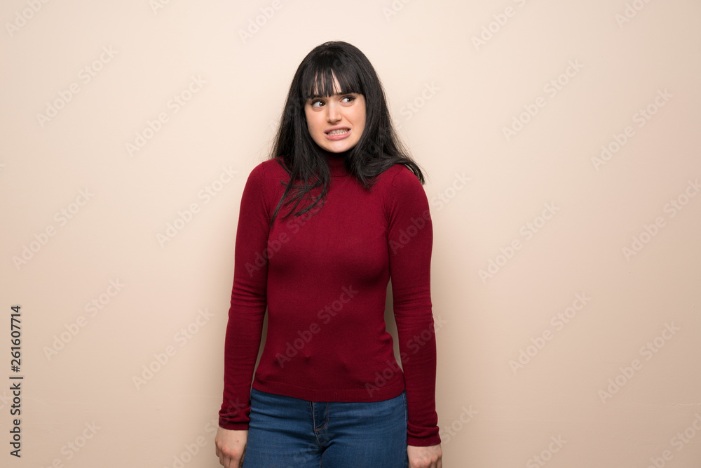 Young woman with red turtleneck is a little bit nervous and scared pressing the teeth Young woman with red turtleneck is a little bit nervous and scared pressing the teeth