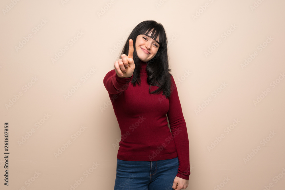 Young woman with red turtleneck showing and lifting a finger Young woman with red turtleneck showing and lifting a finger