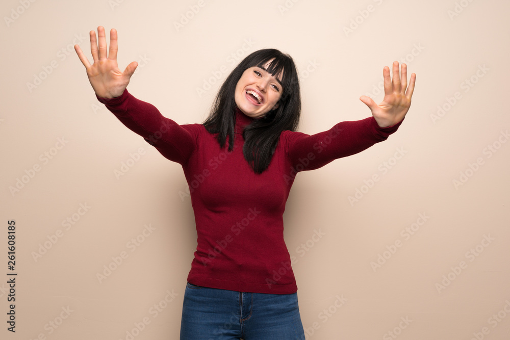 Young woman with red turtleneck counting ten with fingers Young woman with red turtleneck counting ten with fingers