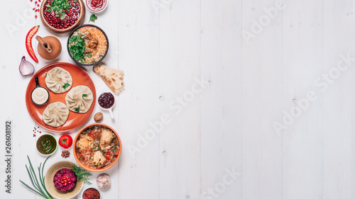 Fototapeta Naklejka Na Ścianę i Meble -  View from above of georgian cuisine on white wooden table. Banner traditional georgian food - khinkali, kharcho, chahokhbili, phali, lobio and local sauces. Top view. Copy space for text