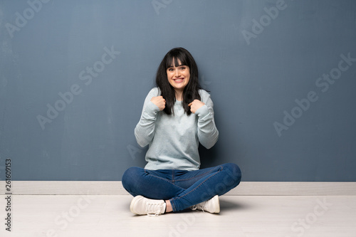 Woman sitting on the floor with surprise facial expression