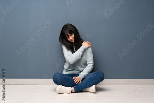 Woman sitting on the floor suffering from pain in shoulder for having made an effort © luismolinero