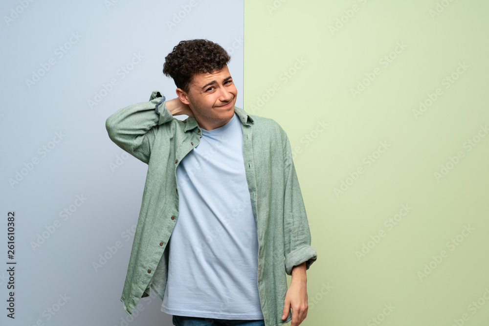 Young man over blue and green background with neckache Young man over blue and green background with neckache