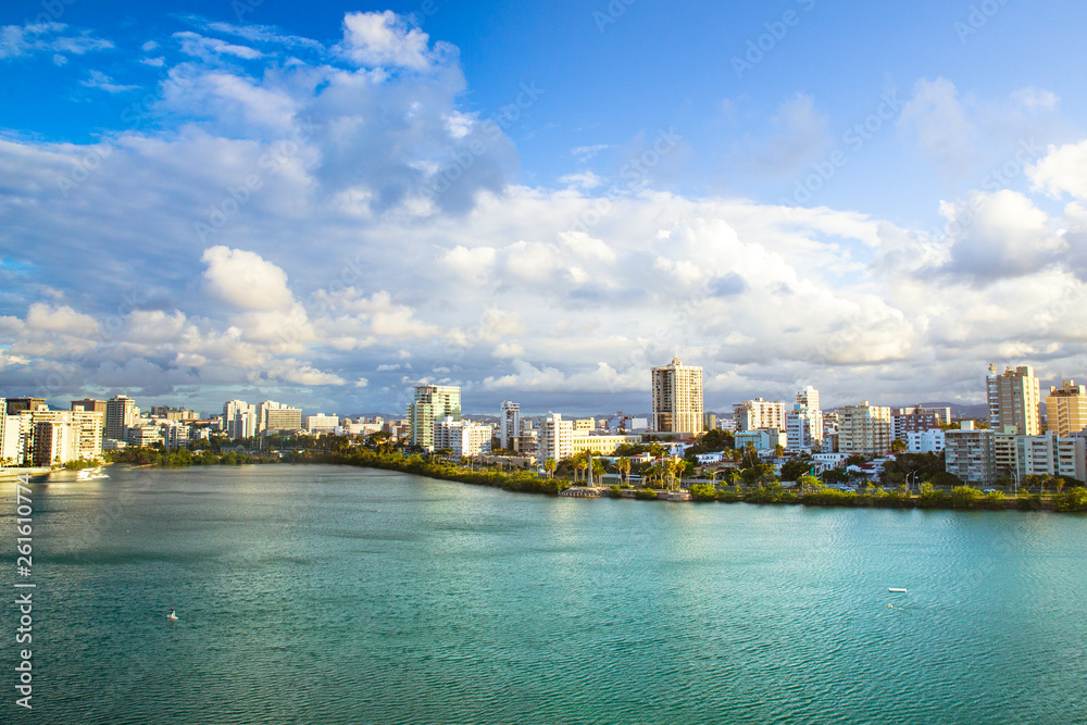 View of Condado area of San Juan Puerto Rico with bay and buildings on a day with clouds and sun.