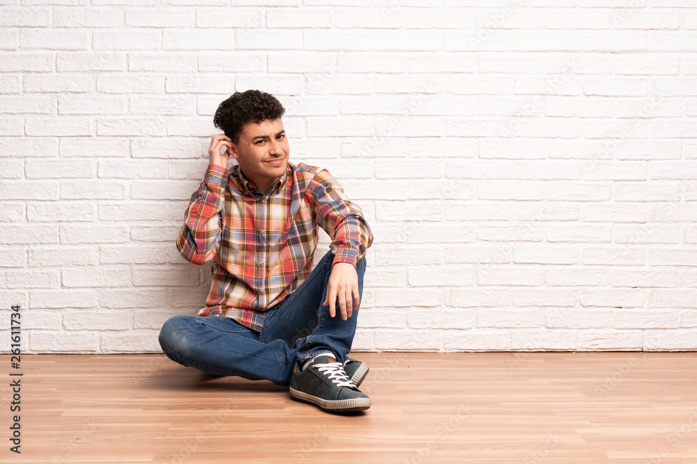 Young man sitting on the floor having doubts Young man sitting on the floor having doubts