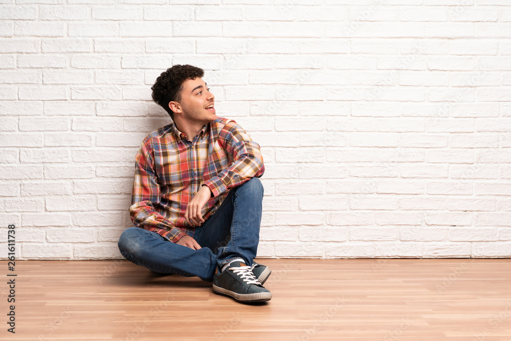 Young man sitting on the floor happy and smiling Young man sitting on the floor happy and smiling