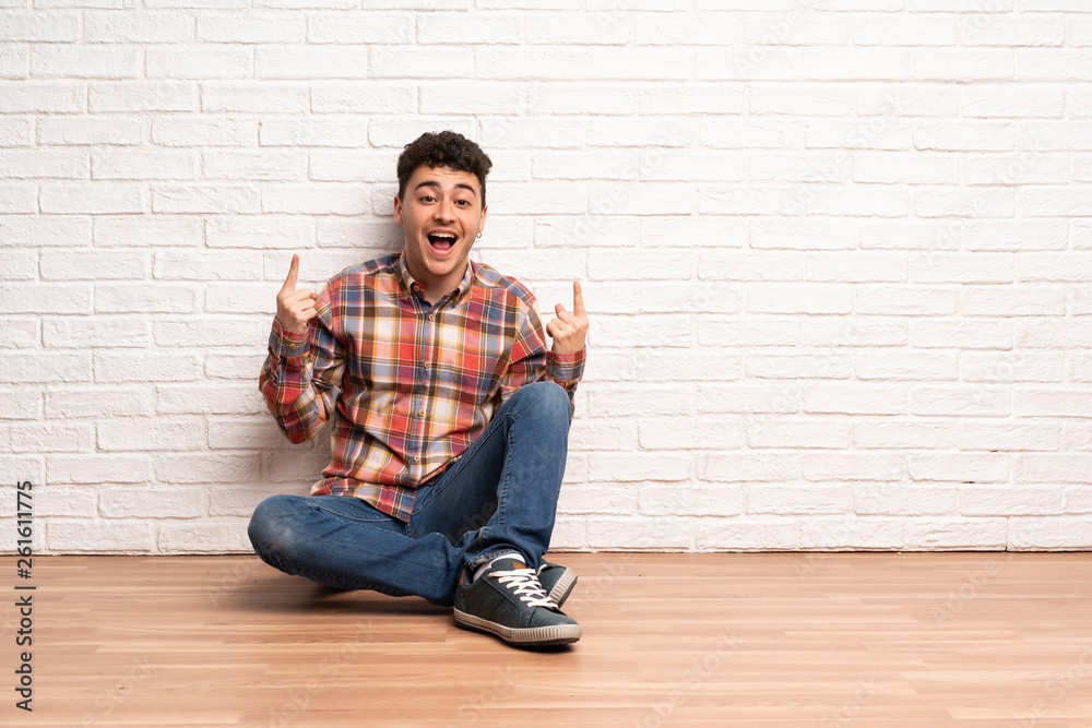 Young man sitting on the floor pointing up a great idea Young man sitting on the floor pointing up a great idea