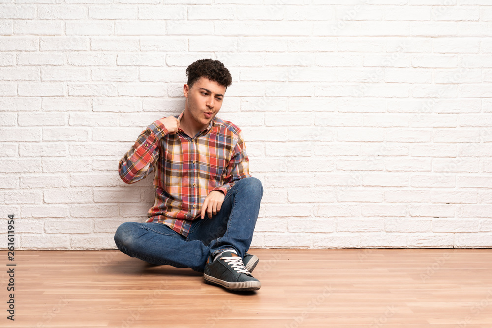Young man sitting on the floor with tired and sick expression Young man sitting on the floor with tired and sick expression