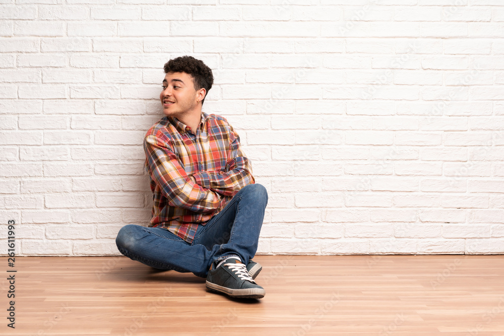 Young man sitting on the floor with arms crossed and happy Young man sitting on the floor with arms crossed and happy