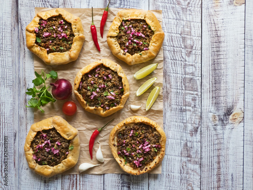 Arabian opened meat pies on white wood background.