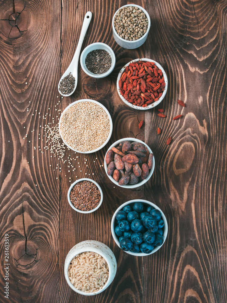 Various superfoods in small bowl on wooden table.Selection super food.Superfood as blueberry, chia, raw cocoa bean, goji, hemp seeds, quinoa, brown rice. Copy space.Top view or flat lay.Vertical Various superfoods in small bowl on wooden table.Selection super food.Superfood as blueberry, chia, raw cocoa bean, goji, hemp seeds, quinoa, brown rice. Copy space.Top view or flat lay.Vertical