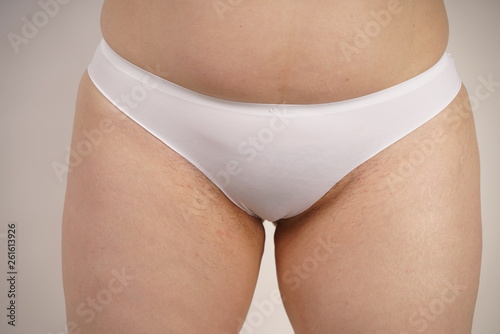 plus size overweight woman with stretches marks on her skin and a hairy crotch standing in white sporty lingerie. female thick hips closeup. unkempt plump girl.